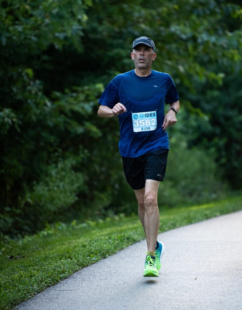 Steve Yeaton running on a tree-lined trail during a race